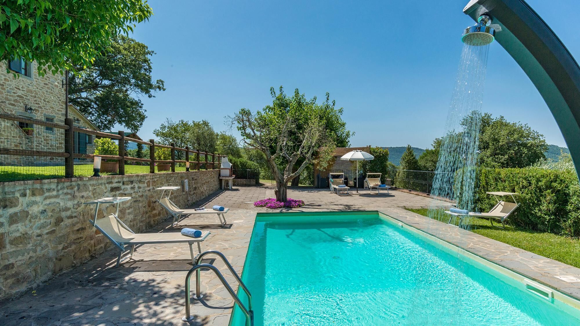 A swimming pool with lounge chairs and a waterfall feature.