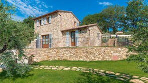 Une maison en pierre avec un mur de pierre et une cour couverte d’herbe.