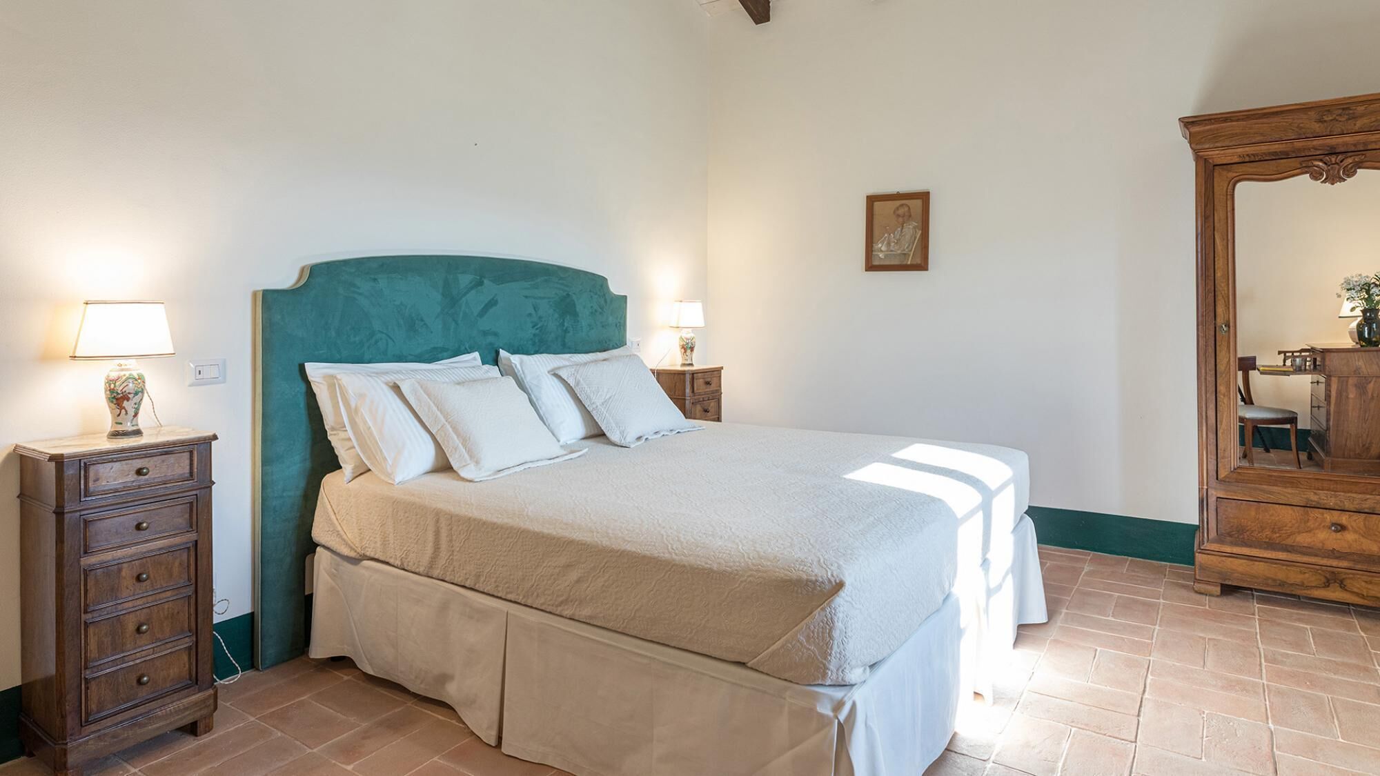 Una camera da letto con un letto, due comodini, una cassettiera, uno specchio e un quadro appeso al muro.