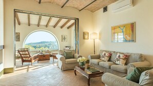 A spacious living room with a large arched window, a sofa set, a coffee table, and a lamp. - Il Colle Di Donna Ilaria 16 (Buonconvento)