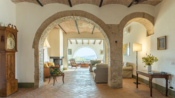 An interior with arched brick ceilings, a fireplace, and a view through a large archway. - Il Colle Di Donna Ilaria 16 (Buonconvento)