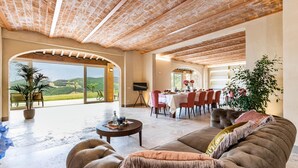 Un amplio salón con un sofá grande, una mesa de comedor para seis personas y una televisión.