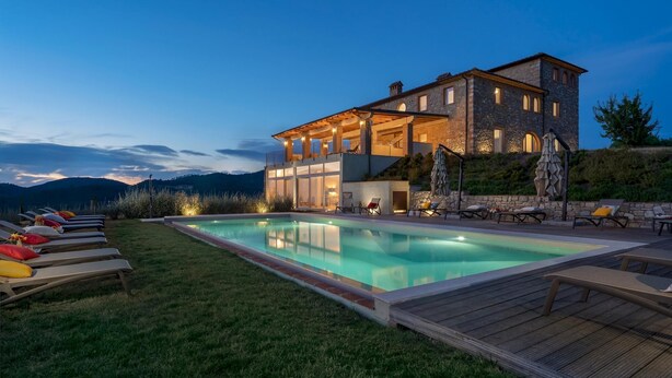 Una casa moderna con piscina, mobiliario exterior y vistas a las montañas.