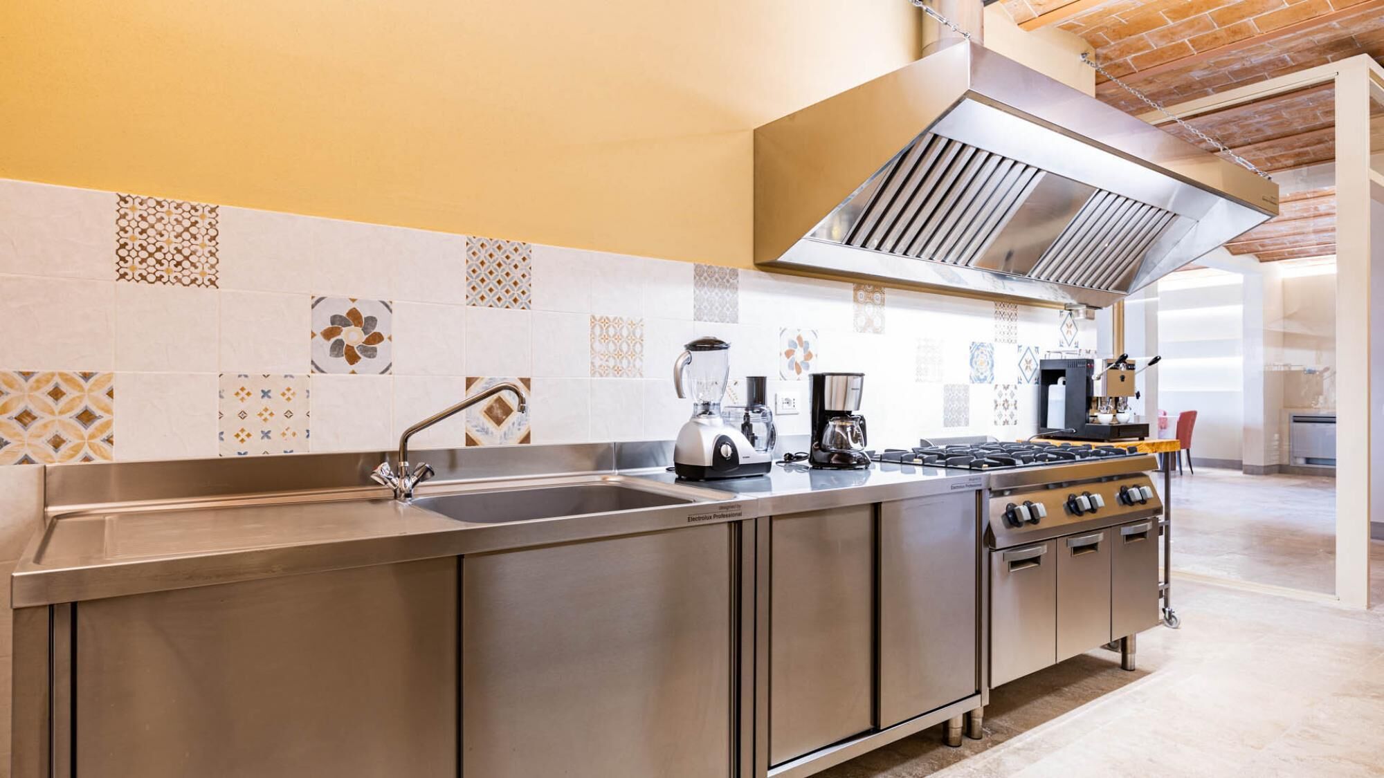 A modern kitchen with stainless steel appliances, a large island, and patterned backsplash tiles.
