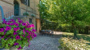 A courtyard with a brick building, outdoor seating, and flowering plants. - Finestra Su Siena 16 (Siena)