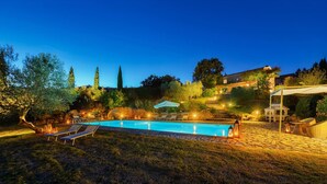 A swimming pool with lounge chairs and a pergola, surrounded by trees and a stone pathway. - Cinque Cipressi 8 in Montecatini Val di Cecina (Montecatini Val di Cecina)
