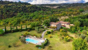 An aerial view of a property with a swimming pool, stone house, and surrounding greenery. - Cinque Cipressi 8 in Montecatini Val di Cecina (Montecatini Val di Cecina)