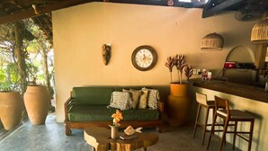 A cozy living area with a green sofa, a wooden coffee table, and a bar area with two wooden chairs.