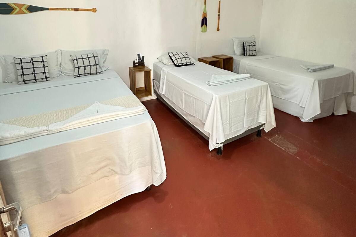 Ein Zimmer mit zwei Betten, einem kleinen Nachttisch und zwei an der Wand befestigten Surfbrettern.