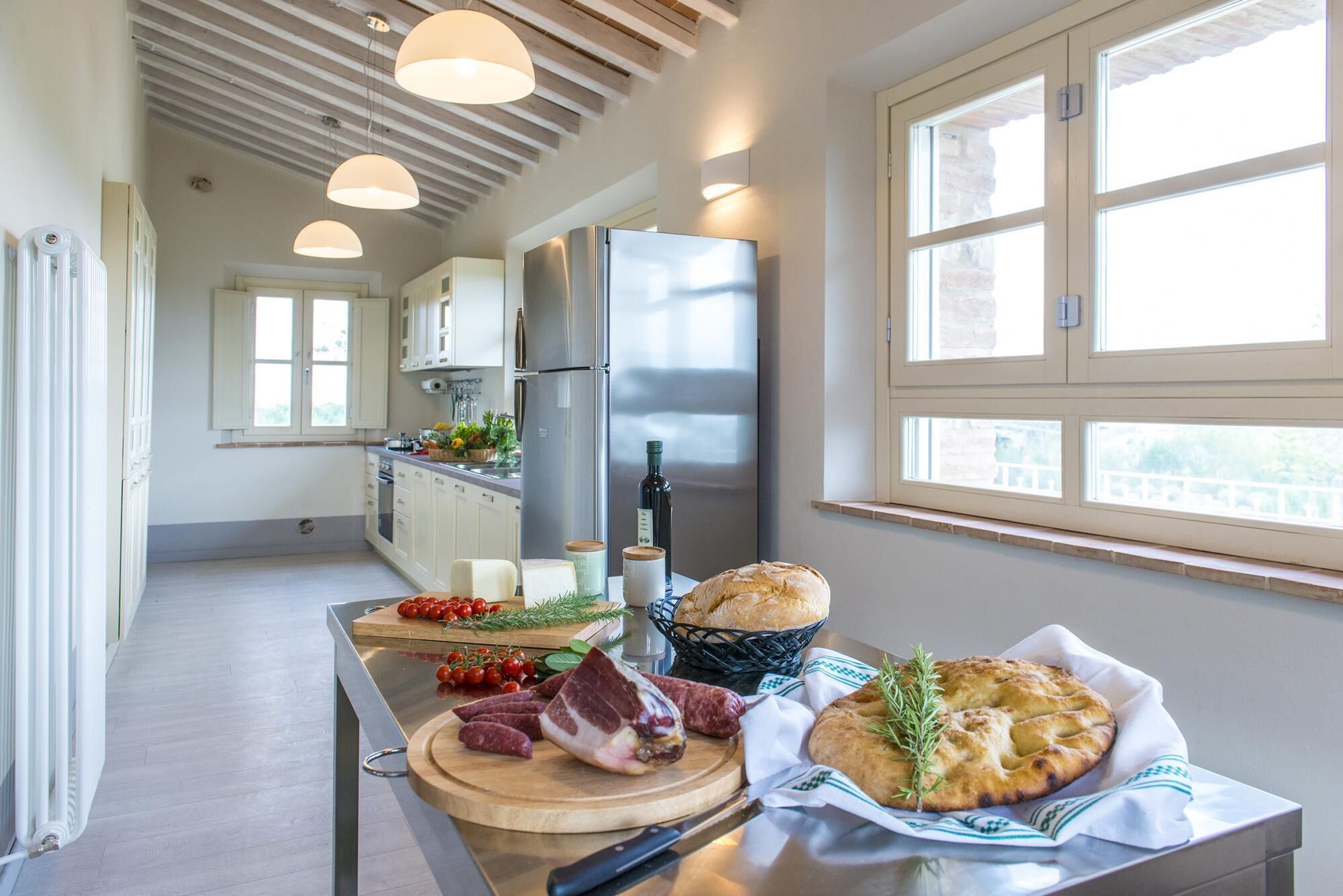A modern kitchen with a stainless steel refrigerator, wooden countertops, and a large window providing natural light.