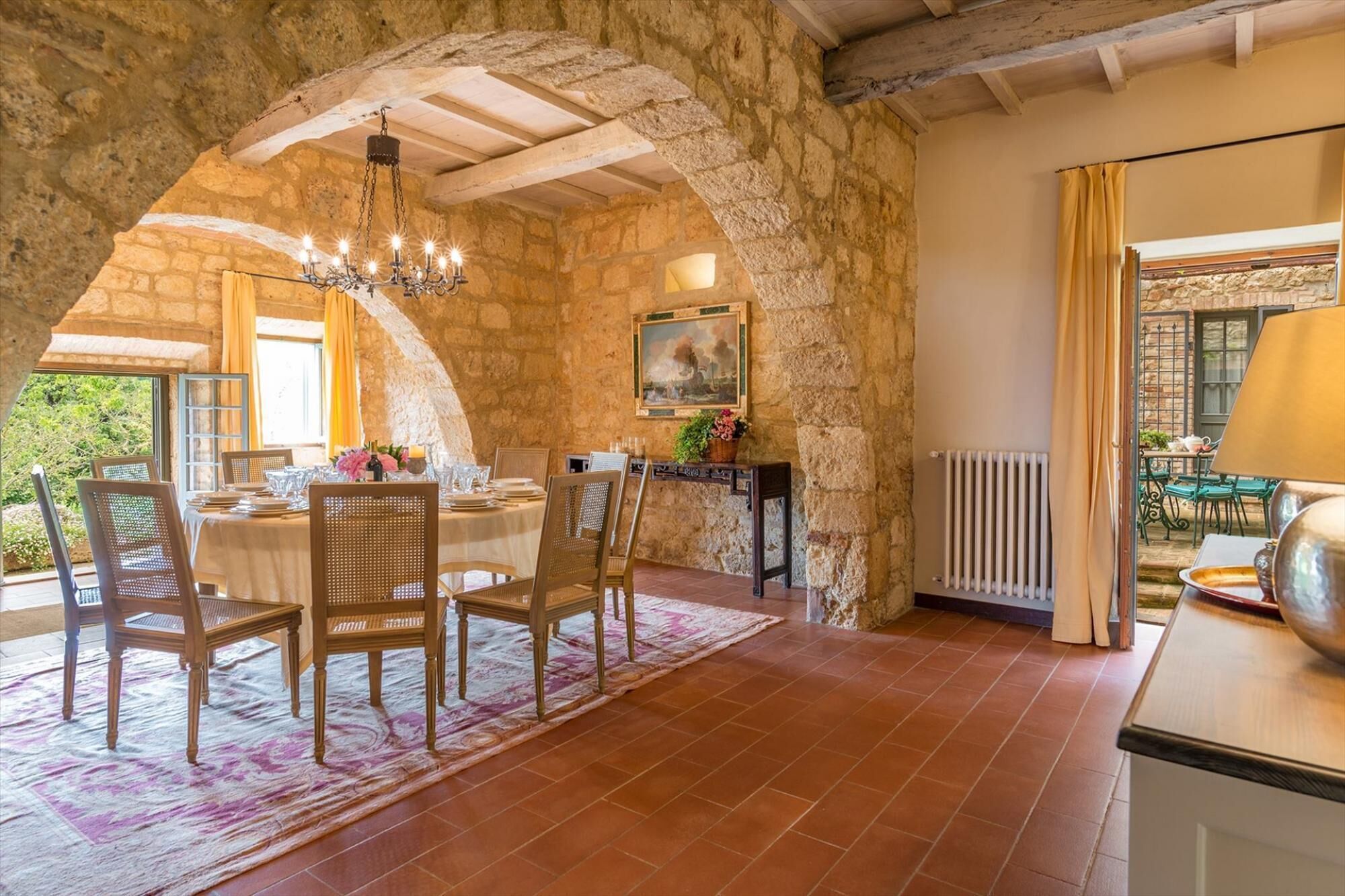 A dining area with stone walls, a chandelier, and a table set for four.