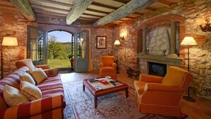 A rustic room with a stone fireplace, a sofa set, and two armchairs.
