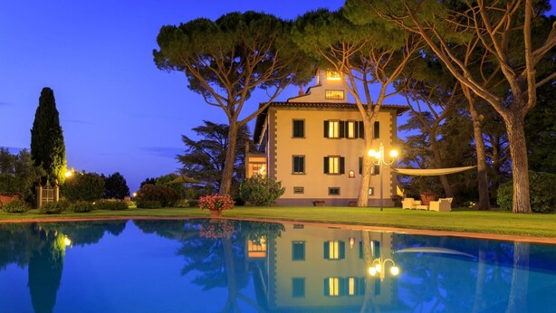 Un bâtiment à deux étages, avec une piscine à l’avant, entouré d’arbres et de pelouses bien entretenues.
