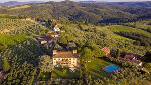 Un vaste domaine comprenant plusieurs bâtiments, une piscine et, au loin, des vignobles.