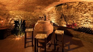 Une cave à vin comprenant un grand tonneau en bois, des bouteilles de vin et une sculpture en verre.