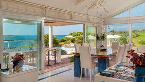 A spacious room with a large glass wall offering a view of the ocean and a pool area. - Villa Ambra 10 in Sorso (Castelsardo)