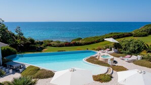 A large, curved swimming pool with a view of the ocean. - Villa Ambra 10 in Sorso (Castelsardo)