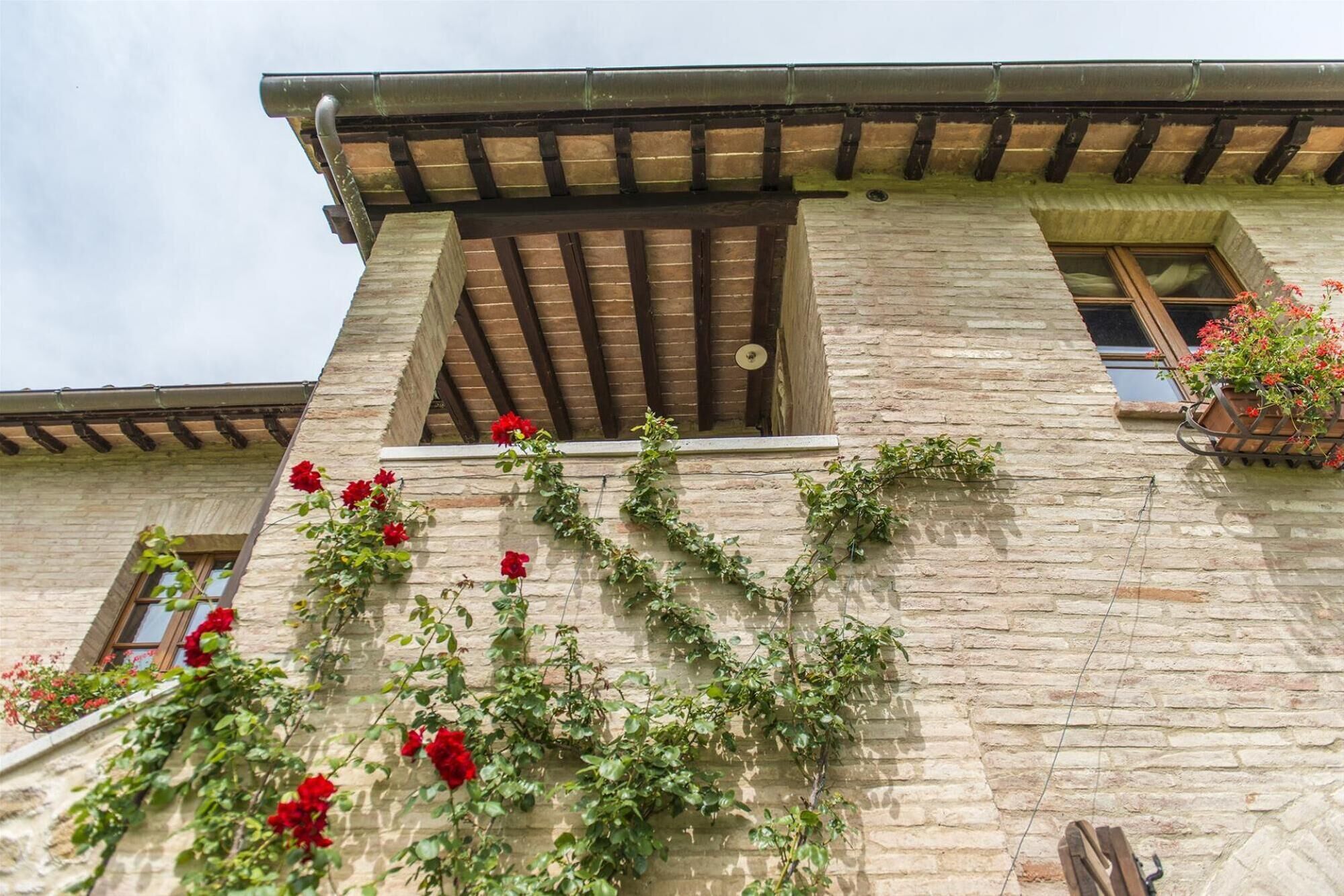 A stone building with a wooden balcony and a window with red flowers.