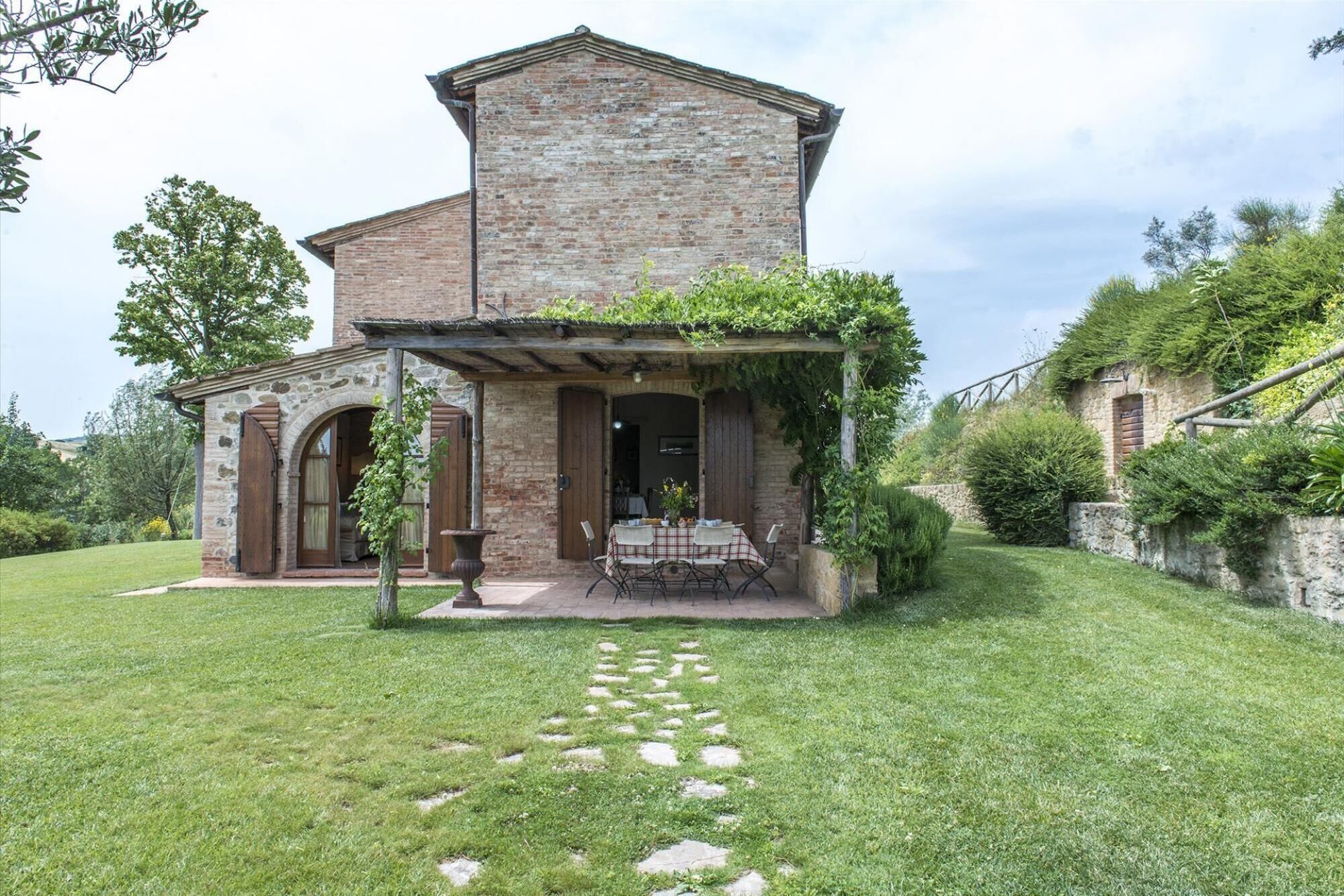 Un bâtiment rustique en pierre, doté d’une terrasse et d’une table dressée pour le repas.