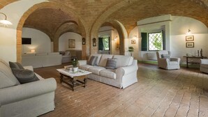A spacious living area with a high, arched brick ceiling, a sofa set, a coffee table, and a small side table.