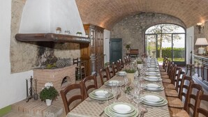 A long dining table set for a meal in a room with a high arched brick ceiling and stone walls.