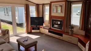 Amplia sala de estar con televisor, chimenea y asientos cómodos.