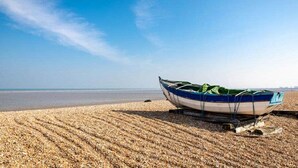 Un bote en una playa de piedras con cielo despejado.
