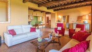 A spacious living area with a white sofa, red armchairs, and a wooden coffee table. - Villa Il Foramasso 10 2 (Casole d'Elsa)