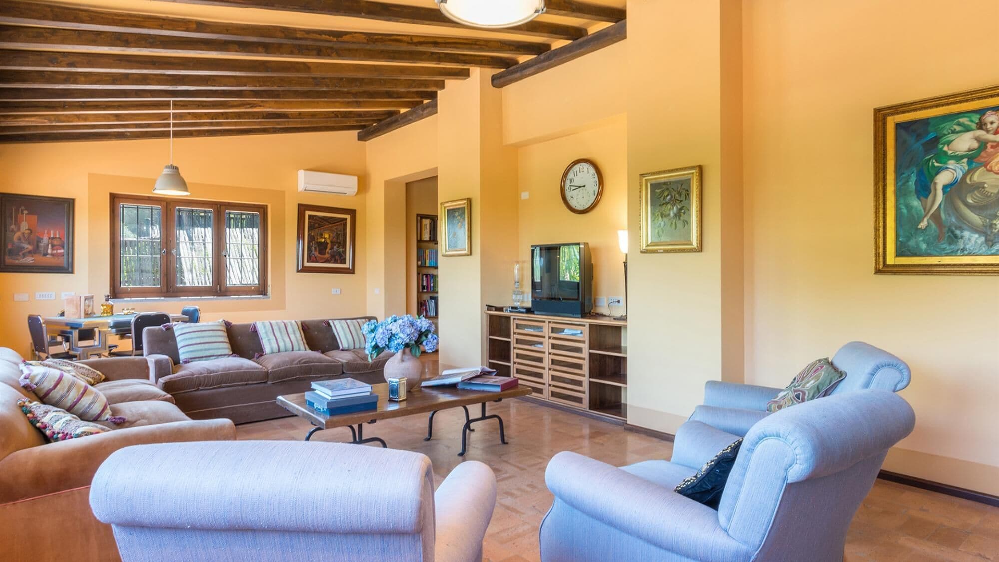 Ein Wohnzimmer mit einer Sofagarnitur, einem Fernseher und einer Wanduhr.
