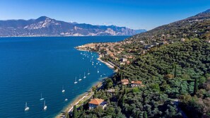 An aerial view of a coastal town with a marina, surrounded by mountains and dense greenery. - Corazza 6 1 in Torri del Benaco (Torri del Benaco)