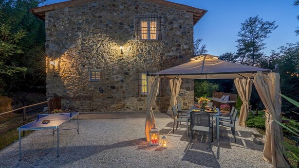 A stone building with a covered outdoor seating area, a ping pong table, and a lantern. - Ai Due Cuori 4 2 in Capannori (Capannori)