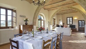 A dining area with a table set for six, a fireplace, and a television in the background. - Alborata 10 in Montalcino (Montalcino)