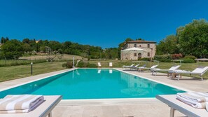 A rectangular swimming pool with a clear blue water surface, surrounded by lounge chairs and sunbeds with towels. - Alborata 10 in Montalcino (Montalcino)