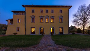 A two-story building with a symmetrical facade, multiple windows, and a central entrance with a door. - Villa Palazzaccio 26 (Arezzo)