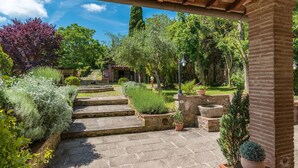 Un jardin avec des marches en pierre menant à une terrasse, entouré de différentes plantes et d’un mur de pierre.