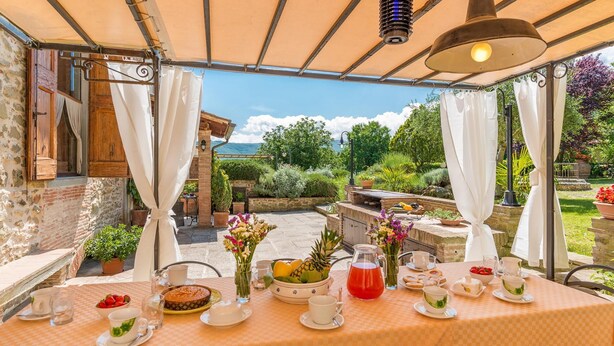 Un espace de restauration en plein air avec une table dressée pour le petit-déjeuner, entouré de murs en pierre et de plantes en pot.