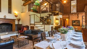 Un vaste espace de vie doté d’une cheminée, d’un canapé en cuir, d’une table à manger pouvant accueillir six personnes et d’un escalier menant à l’étage supérieur.
