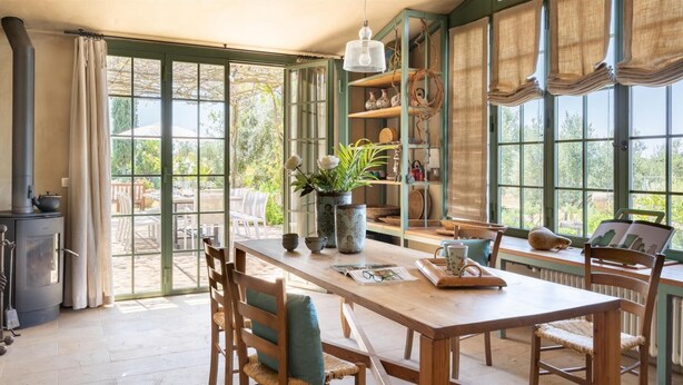 A spacious dining area with a wooden table, chairs, and a view of the garden through large windows. - Casa Del Vento 10 in Bibbona (Bibbona)