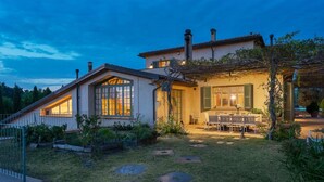 A two-story house with a patio area, a dining table with chairs, and a garden with a fence. - Casa Del Vento 10 in Bibbona (Bibbona)
