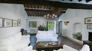 Ein geräumiges Wohnzimmer mit weißen Sofas, einem Steinkamin und einer Kristallleuchtre.