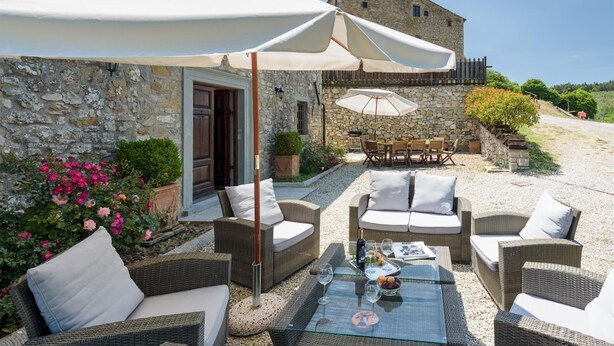 A patio with wicker furniture, a glass table, and umbrellas. - Villa La Poiana 10 in Radda in Chianti (Radda in Chianti)