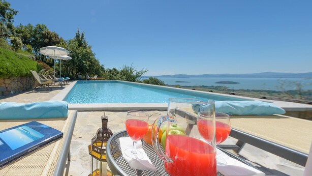 A poolside view with a laptop, drinks, and a bottle. - Antiche Pietre 10 in Tuoro sul Trasimeno (Tuoro sul Trasimeno)