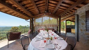 A covered outdoor dining area with a table set for four, overlooking a scenic landscape. - Antiche Pietre 10 in Tuoro sul Trasimeno (Tuoro sul Trasimeno)