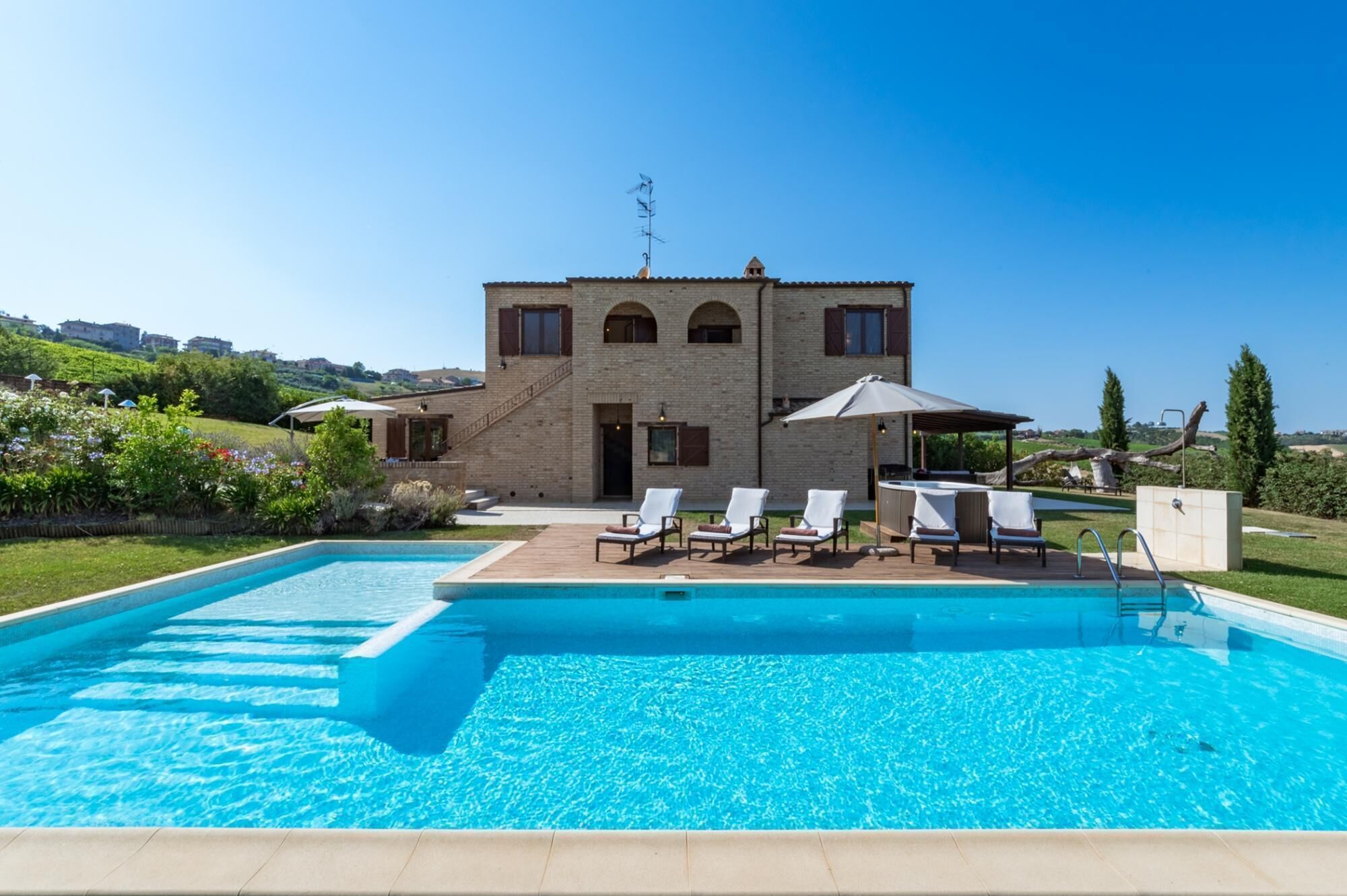 A two-story house with a swimming pool and outdoor seating.
