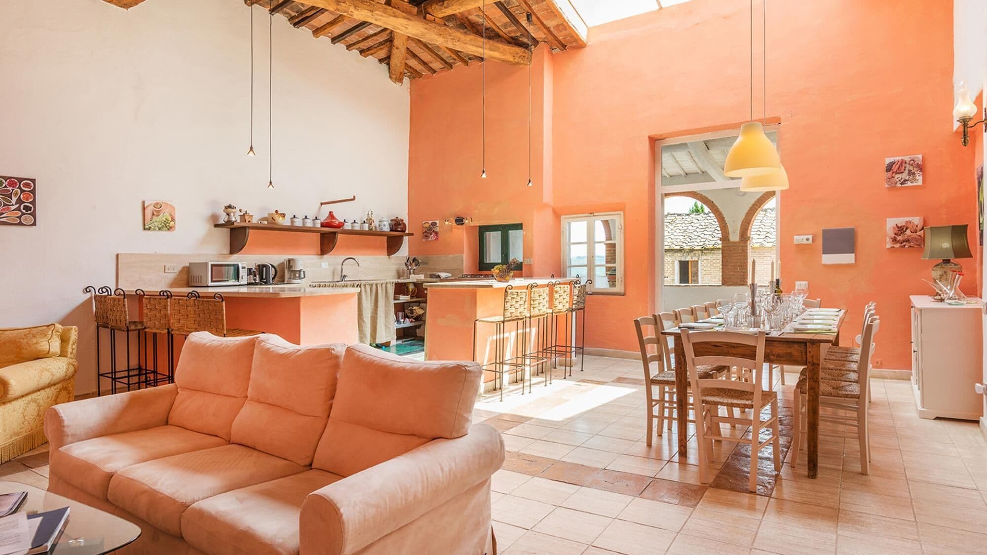 A cozy living room with a sofa, a dining area with a table set for four, and a kitchen with a bar area.