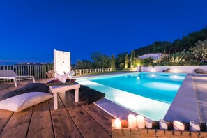 A swimming pool with a wooden deck, lounge chairs, and candles. - Casa Angela 6 in Monte Urano (Monte Urano)