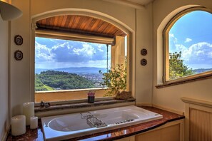 A bathroom with a large window offering a scenic view of a hilly landscape.