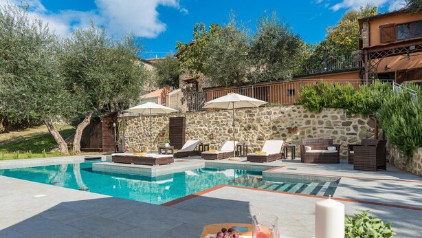 A swimming pool with lounge chairs and umbrellas, surrounded by stone walls and greenery. - Casale Montegiovi 6 4 (Castel del Piano)