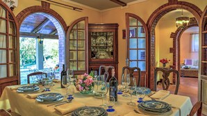 A dining area with a table set for six, surrounded by arched brick walls and a large china cabinet. - Casale Le Conce 6 (Castel del Piano)