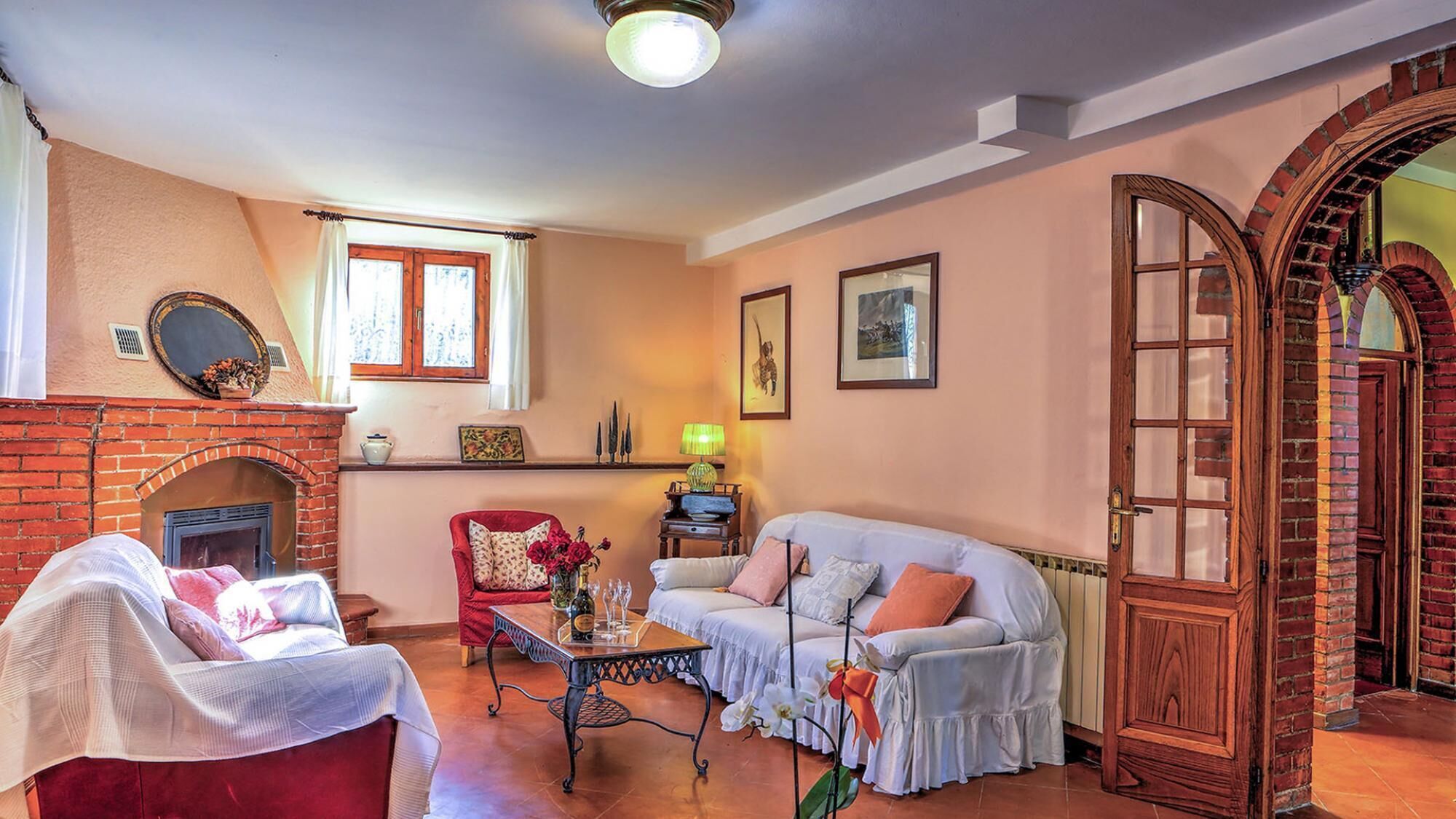 A cozy living room with a fireplace, a red armchair, a sofa, and a coffee table.